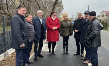 Grupa przedsawicieli lokalnych władz stojąca przy zmidernizowanej drodze